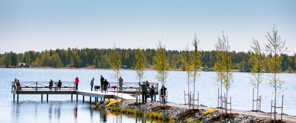 En kort trädallé leder ut till en brygga med flera personer på