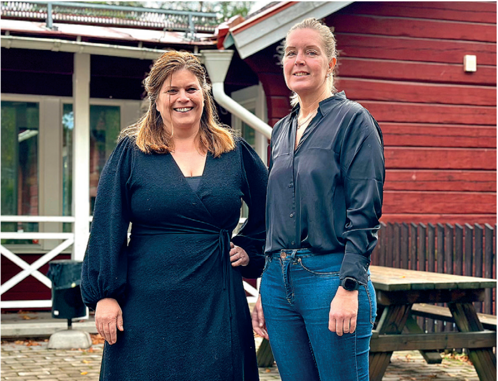Två kvinnor framför ett rött hus